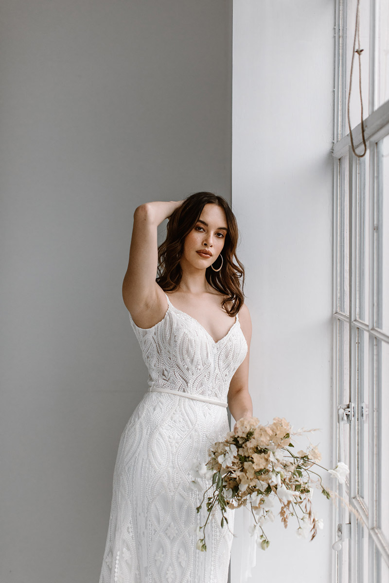 Our beaded ivory Lennon wedding dress is romance caught in a web of textured bead work that creates unique interest and a fitted shape.