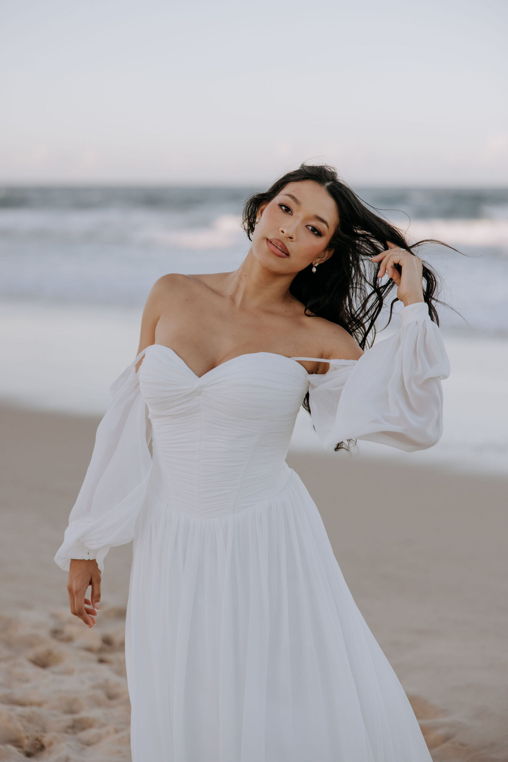 The mermaid off the shoulder silhouette of our Paloma wedding dress enhances your curves with the artful placement of the leafy vine lace applique design.